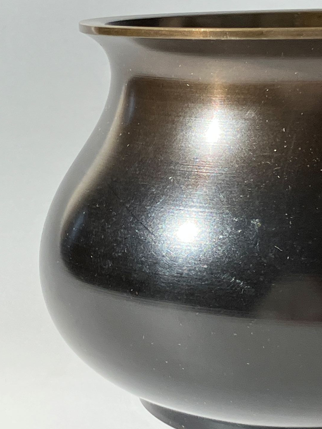 Close-up of a metallic object with a reflective surface on a white background