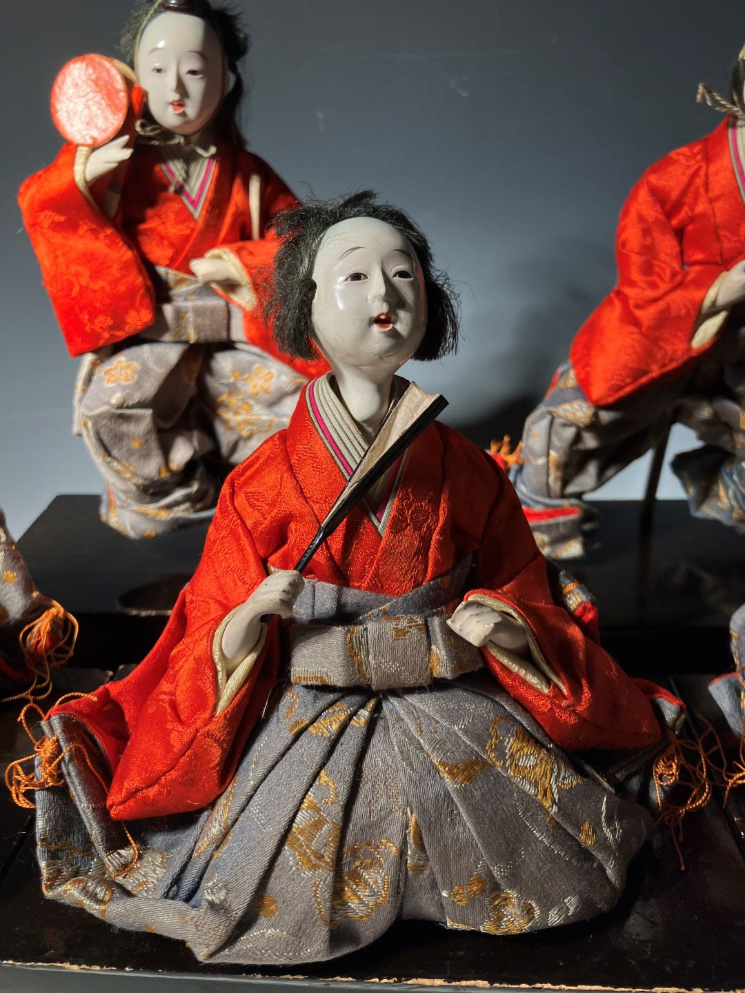 Traditional Japanese dolls in red and gray costumes against a dark background