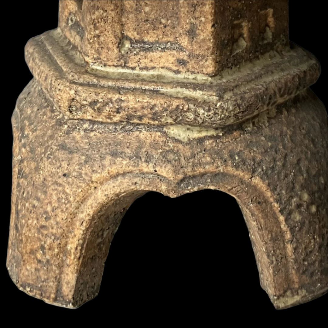 Close-up of the base of a vintage Japanese ceramic temple lantern in Ishidoro design, showcasing the textured surface and elegantly arched feet.