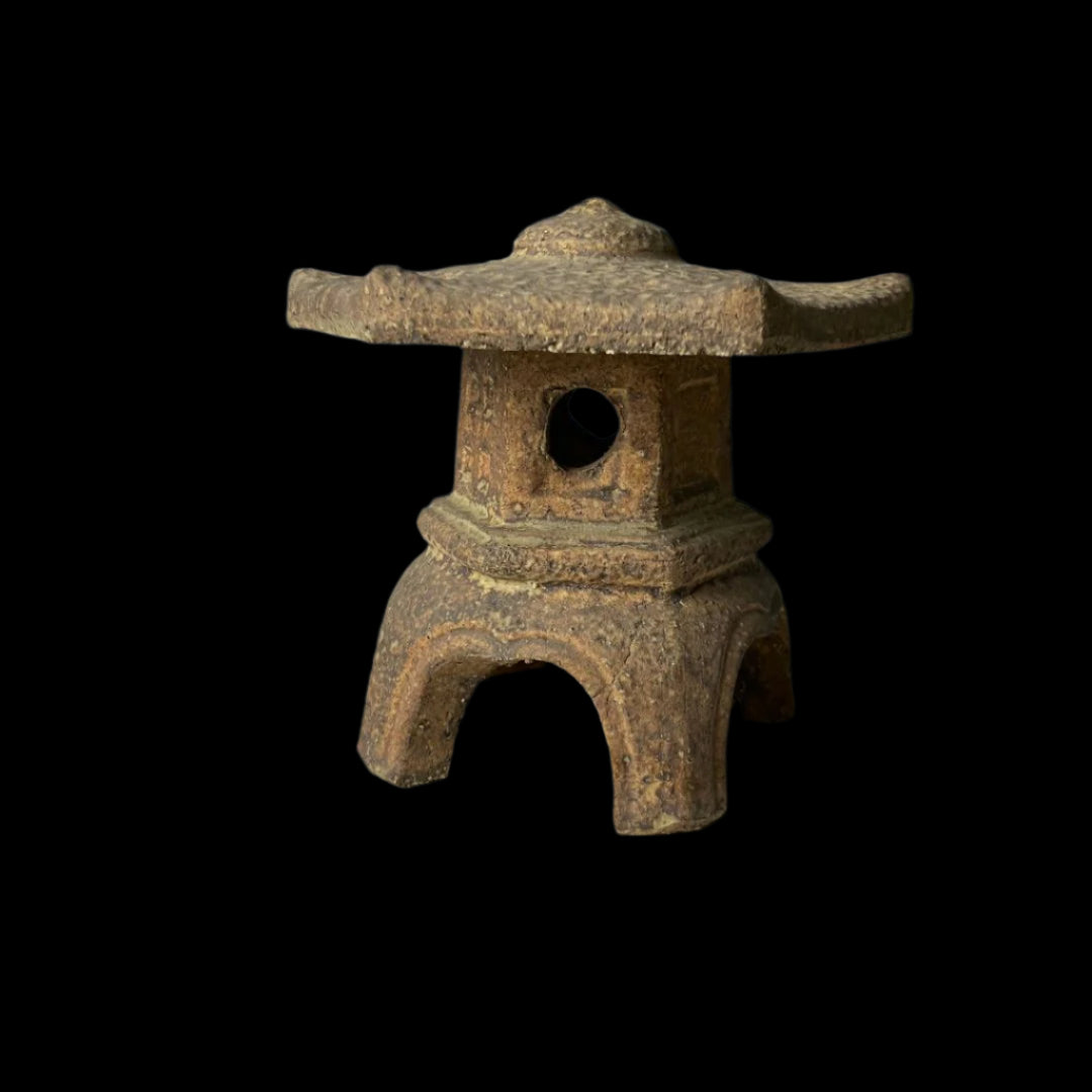 Side view of a vintage Japanese ceramic temple lantern in Ishidoro design, showcasing a textured finish, circular cut-out details, and traditional pagoda-inspired structure.