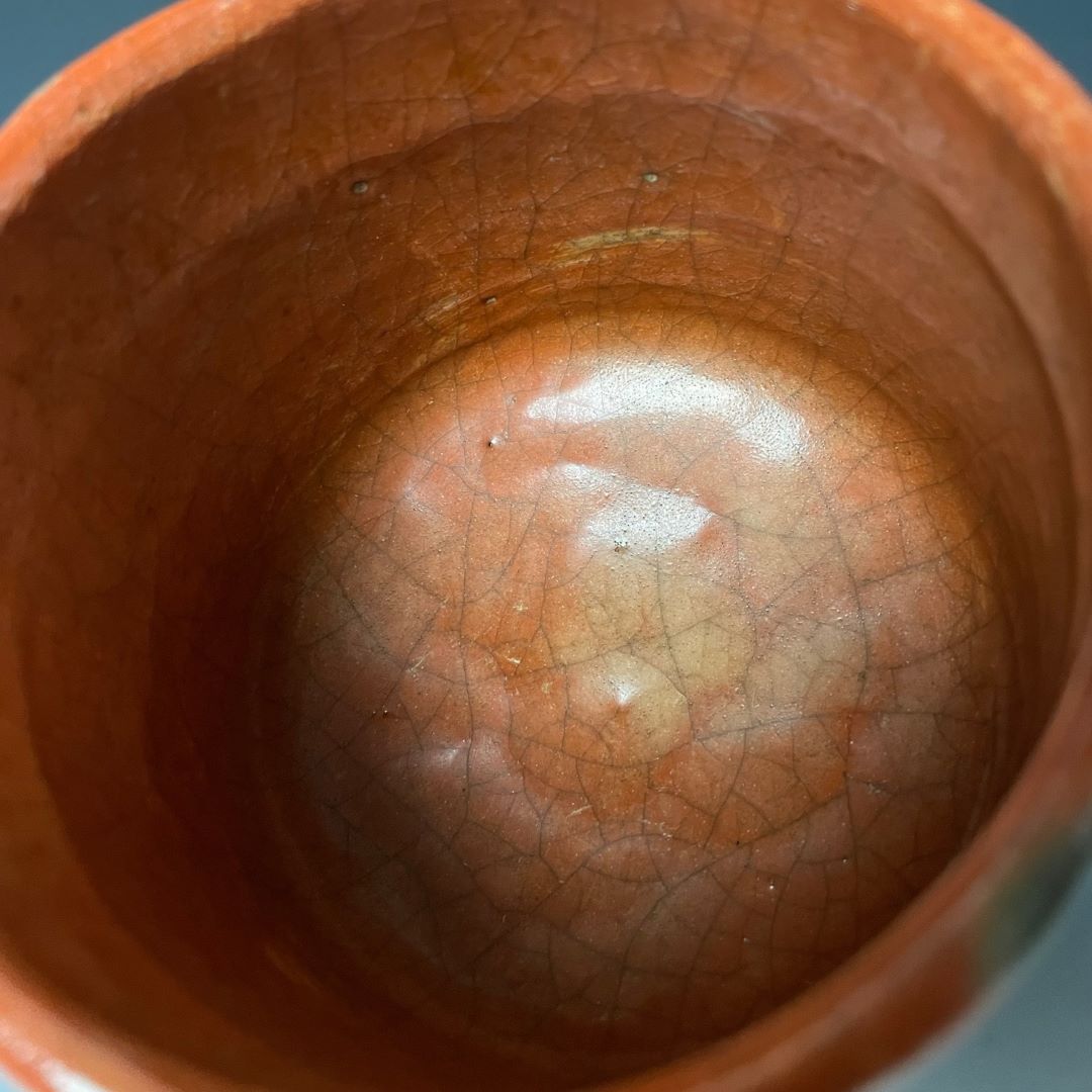 Close-up view of the interior of a traditional Japanese Raku yaki tea bowl, displaying a rich, crackled glaze in orange tones that highlight the unique texture and craftsmanship of the pottery.