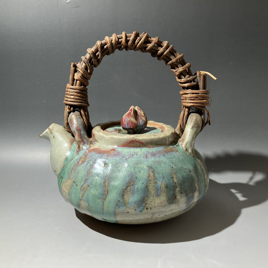 Ceramic teapot with textured handle on a gray background