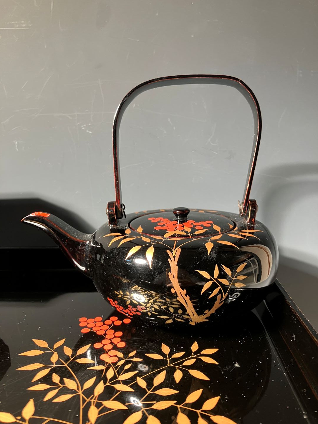 Decorative teapot with floral patterns on a reflective surface