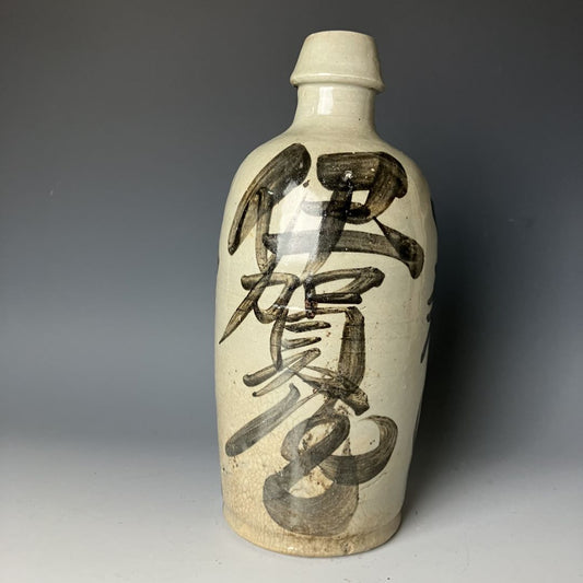 A traditional Japanese ceramic Tokkuri sake bottle with calligraphy design on a crackled white glaze background.