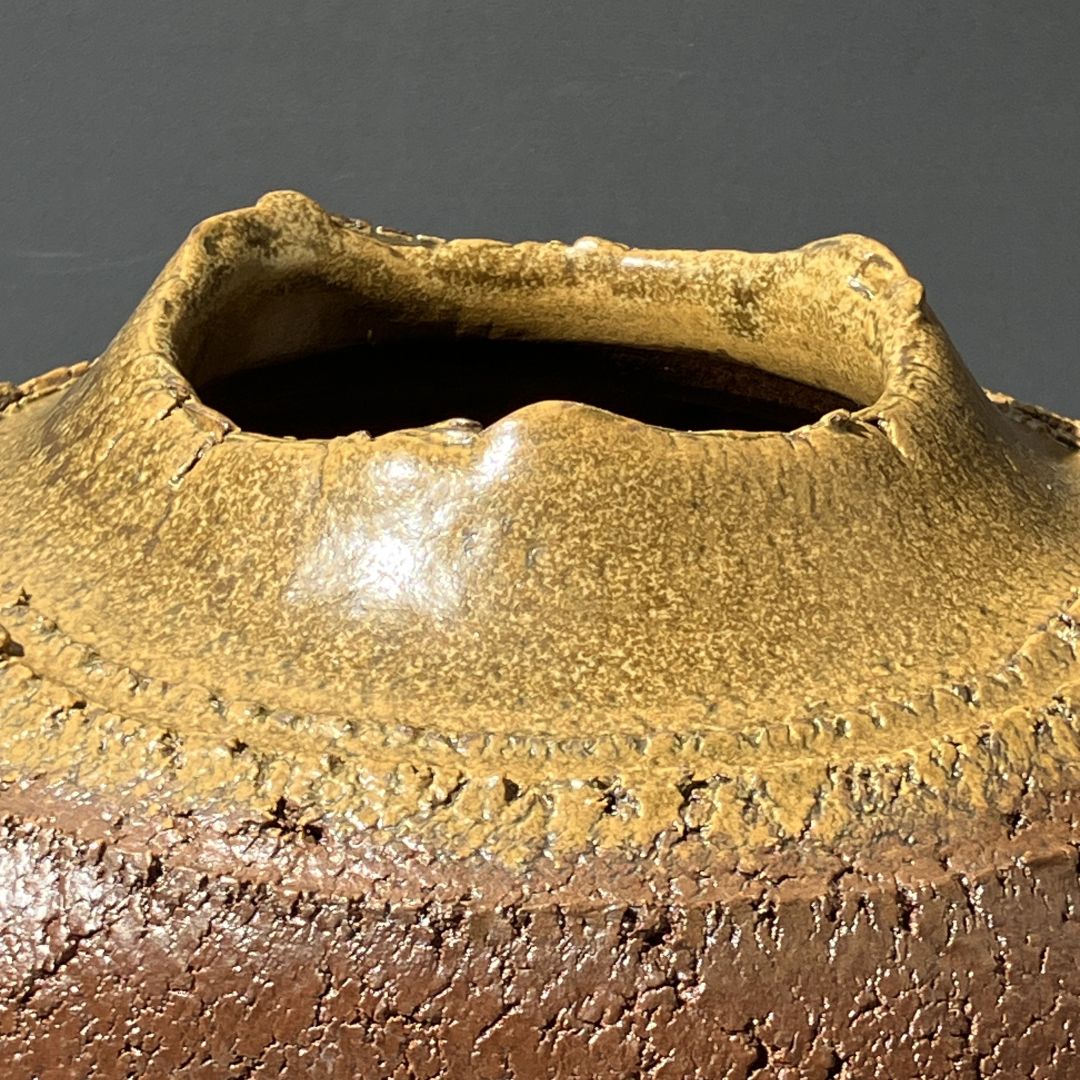 Close-up of a ceramic pot with textured surface and dark gray background