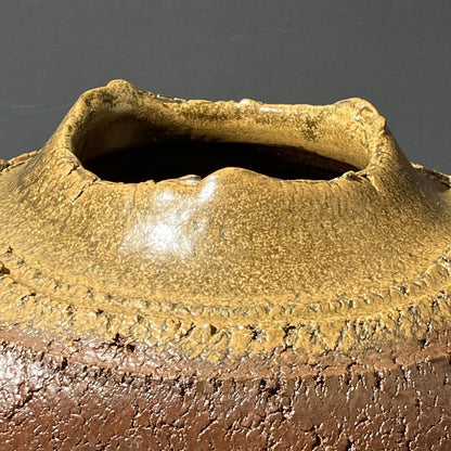Close-up of a ceramic pot with textured surface and dark gray background