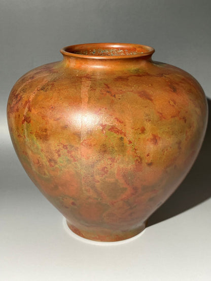 Vase with marbled orange and green design on a gray background
