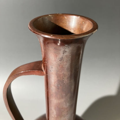 Copper pitcher with a handle on a gray background