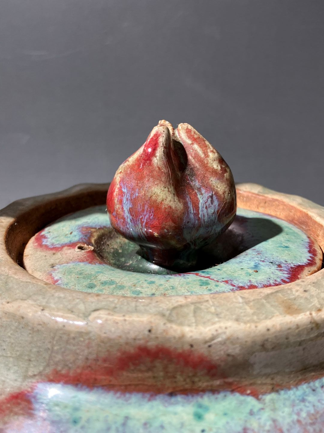 Close-up of a ceramic vase with textured surface and colorful glaze.