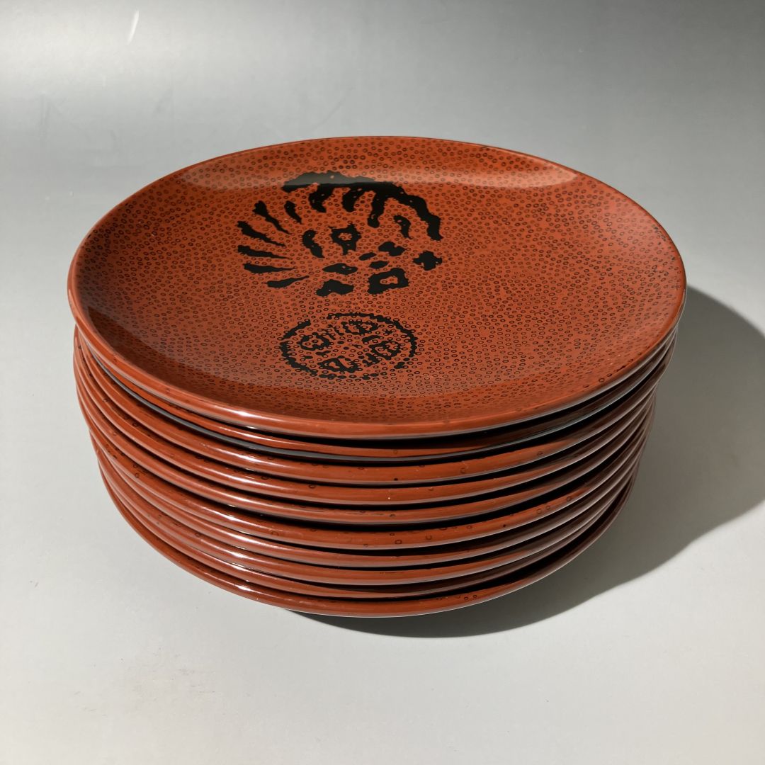 Stack of brown ceramic plates with black patterns on a gray background