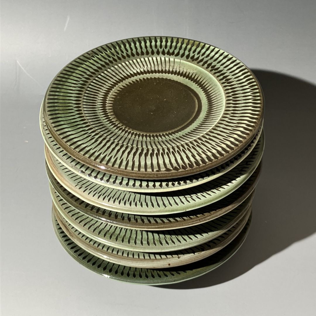 Stack of ceramic plates with decorative patterns on a light gray background