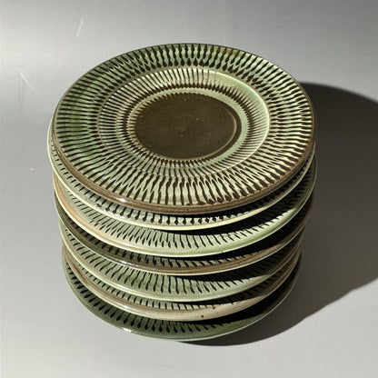Stack of ceramic plates with decorative patterns on a light gray background