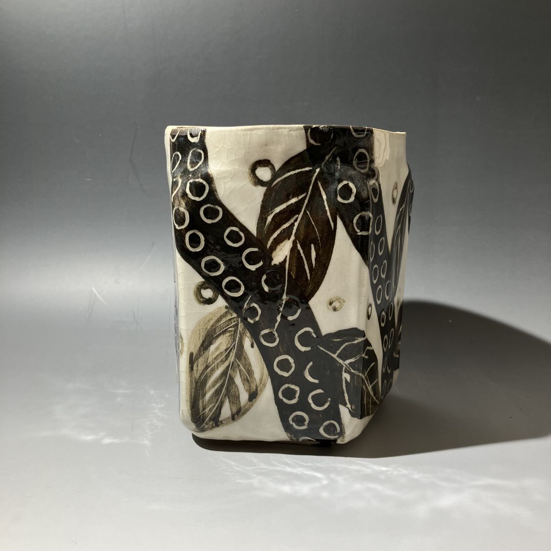 Ceramic vase with black and white leaf pattern on a gray background
