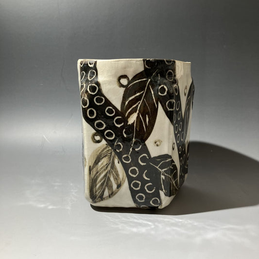 Ceramic vase with black and white leaf pattern on a gray background