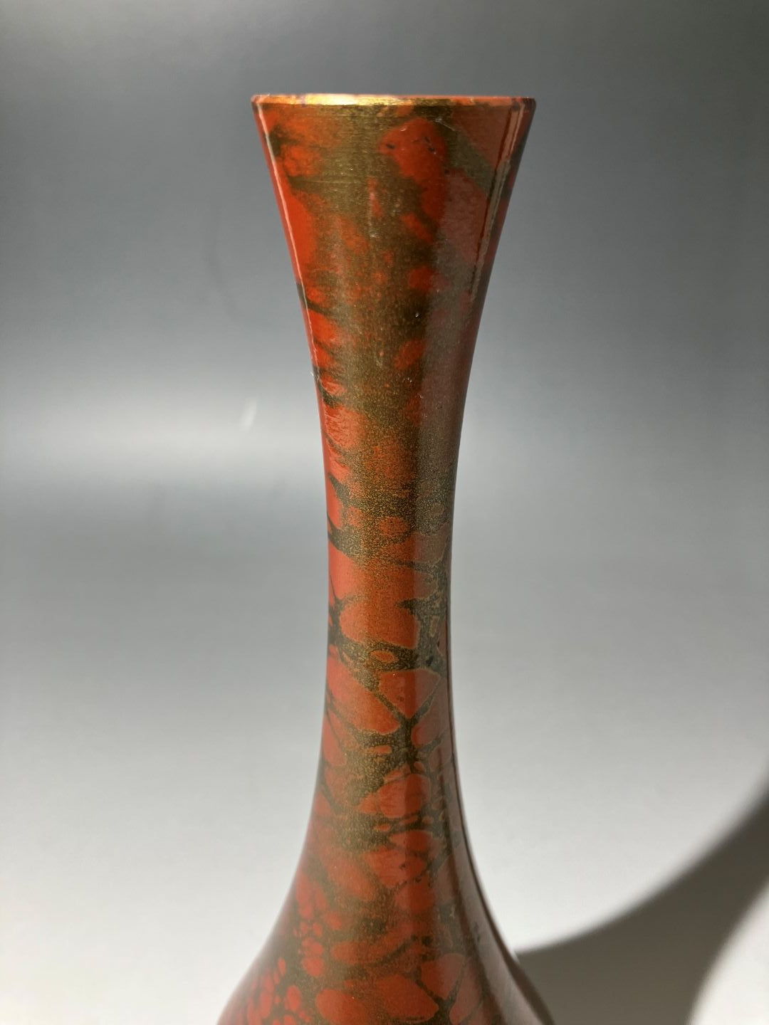 Close-up of a red and gold decorative object on a gray background