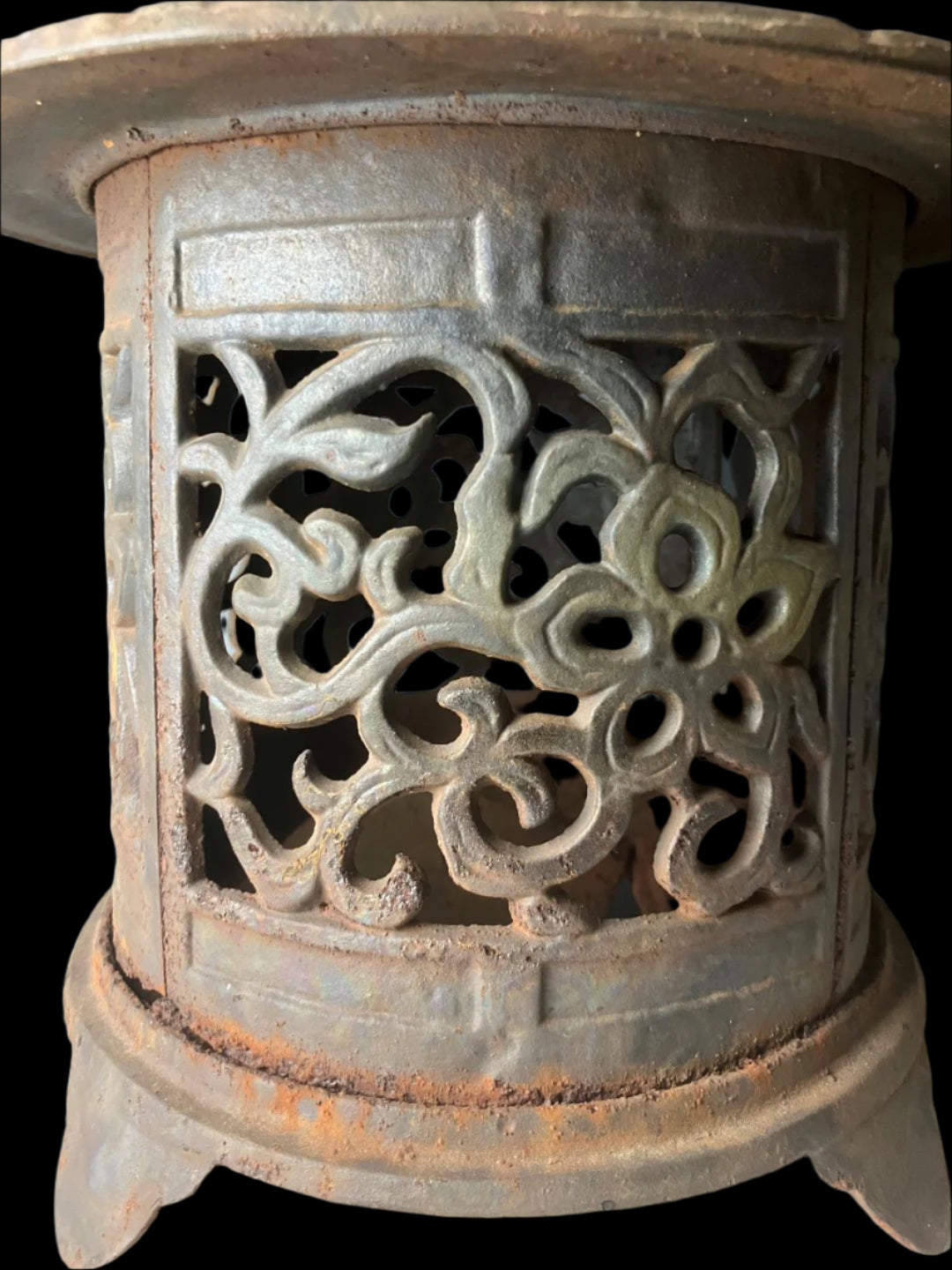 Close-up view of an antique Japanese cast iron lantern, focusing on the intricate arabesque designs. The metal surface shows rust and patina, emphasizing its age and authenticity.