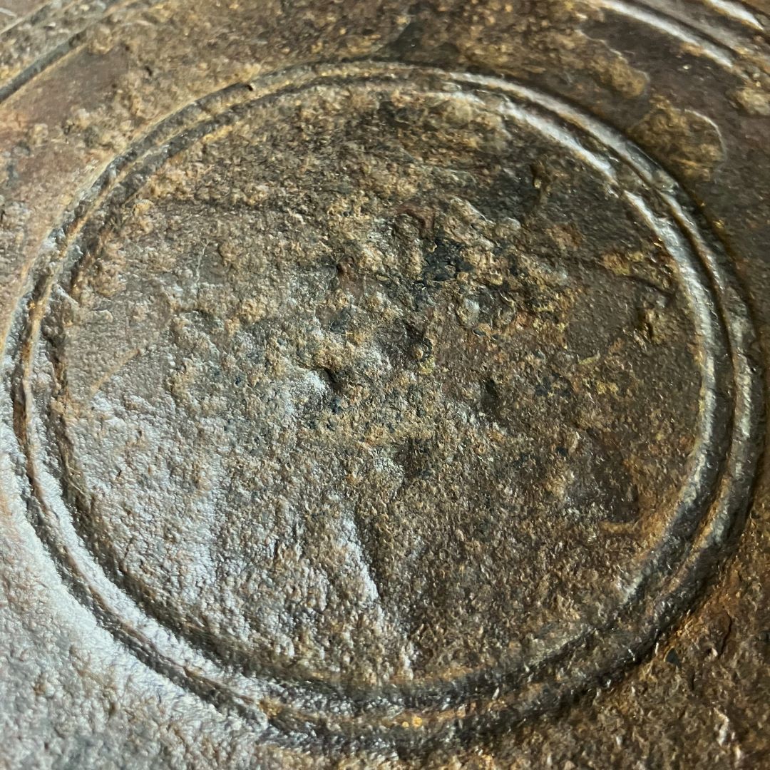 Close-up of the weathered surface of a Waniguchi gong, highlighting the concentric circle pattern etched into the metal, with a textured patina from age and use.