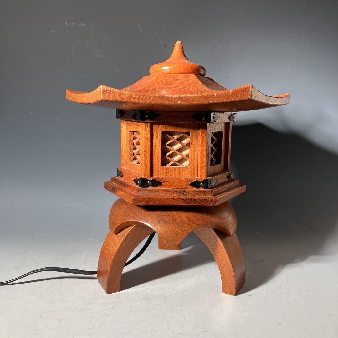 Vintage Japanese wooden pagoda-style lantern lamp handcrafted with lattice windows and curved roof, featuring black metal details and an electric cord, displayed against a neutral background.
