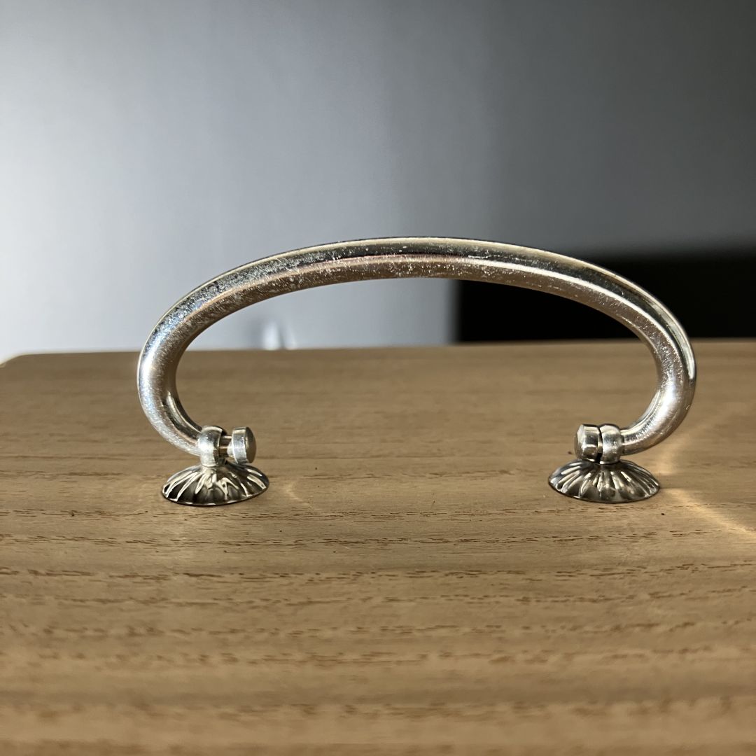 Decorative metal handle on a wooden surface with a neutral background