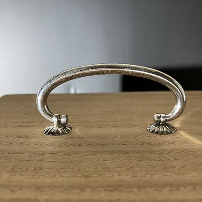 Decorative metal handle on a wooden surface with a neutral background