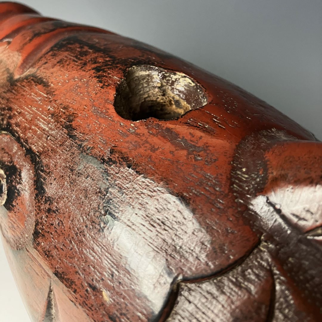 A close-up image showing the detailed tail section of an antique Japanese wooden fish carving. The surface has a lustrous, deep reddish-brown finish with visible wear and scuff marks that add character to the piece