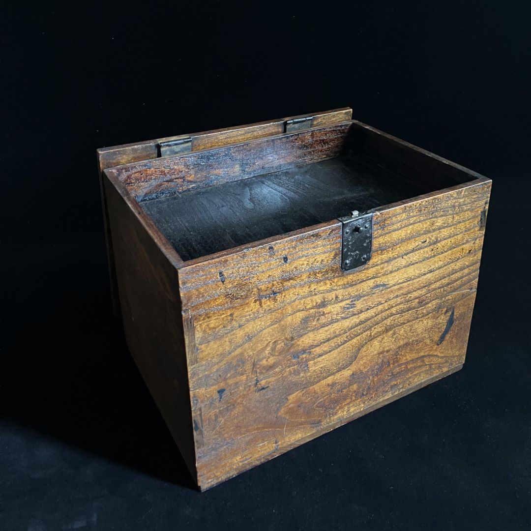 Antique wooden writing cabinet with open drawers, side view in a black room.