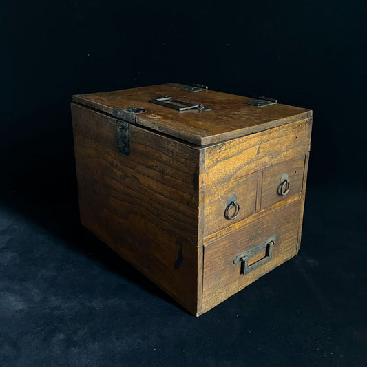  Antique wooden writing cabinet in side view against a black room background.
