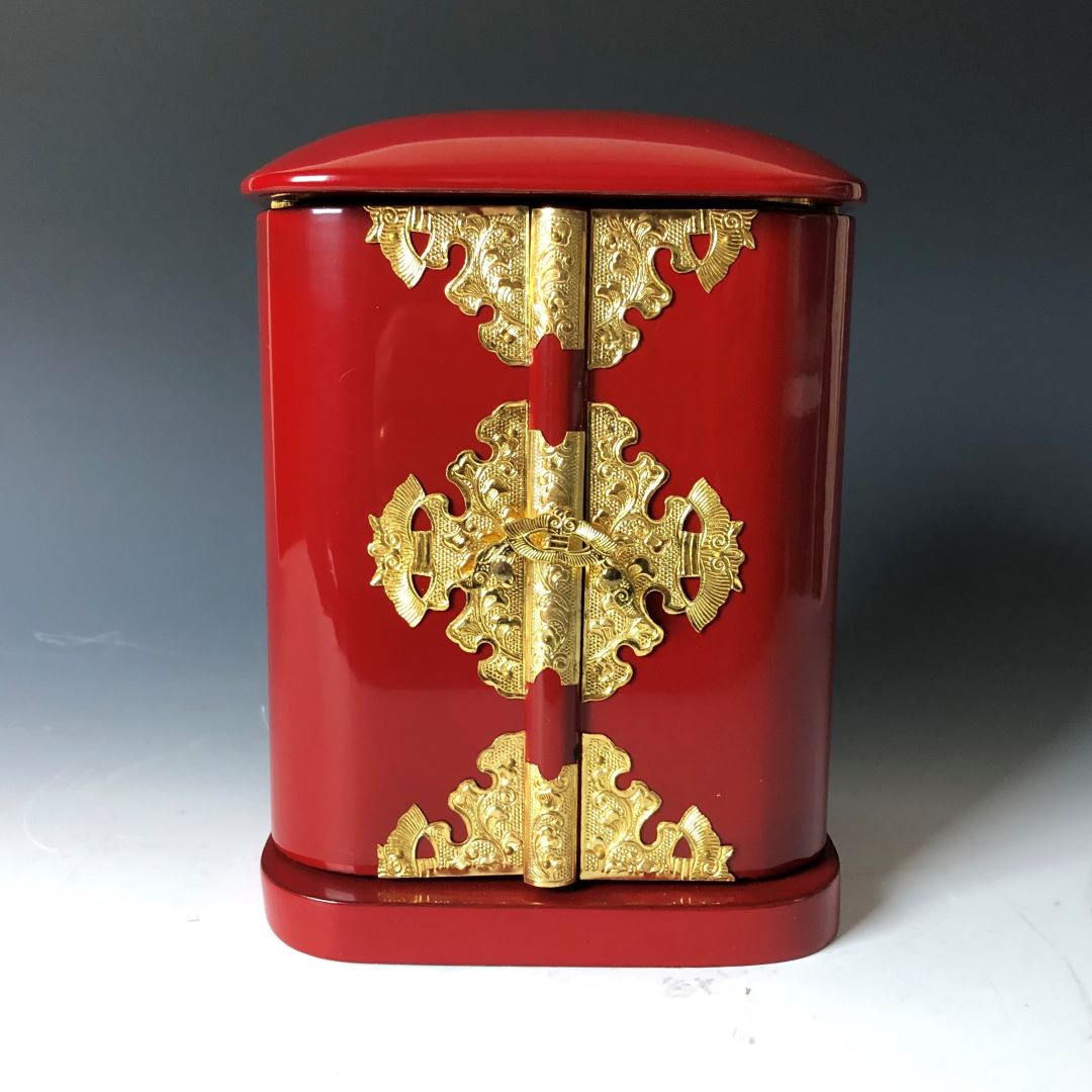 A closed Japanese vintage Zushi cabinet with a vibrant red finish and ornate golden metalwork on the hinges and clasps, displaying traditional design elements.