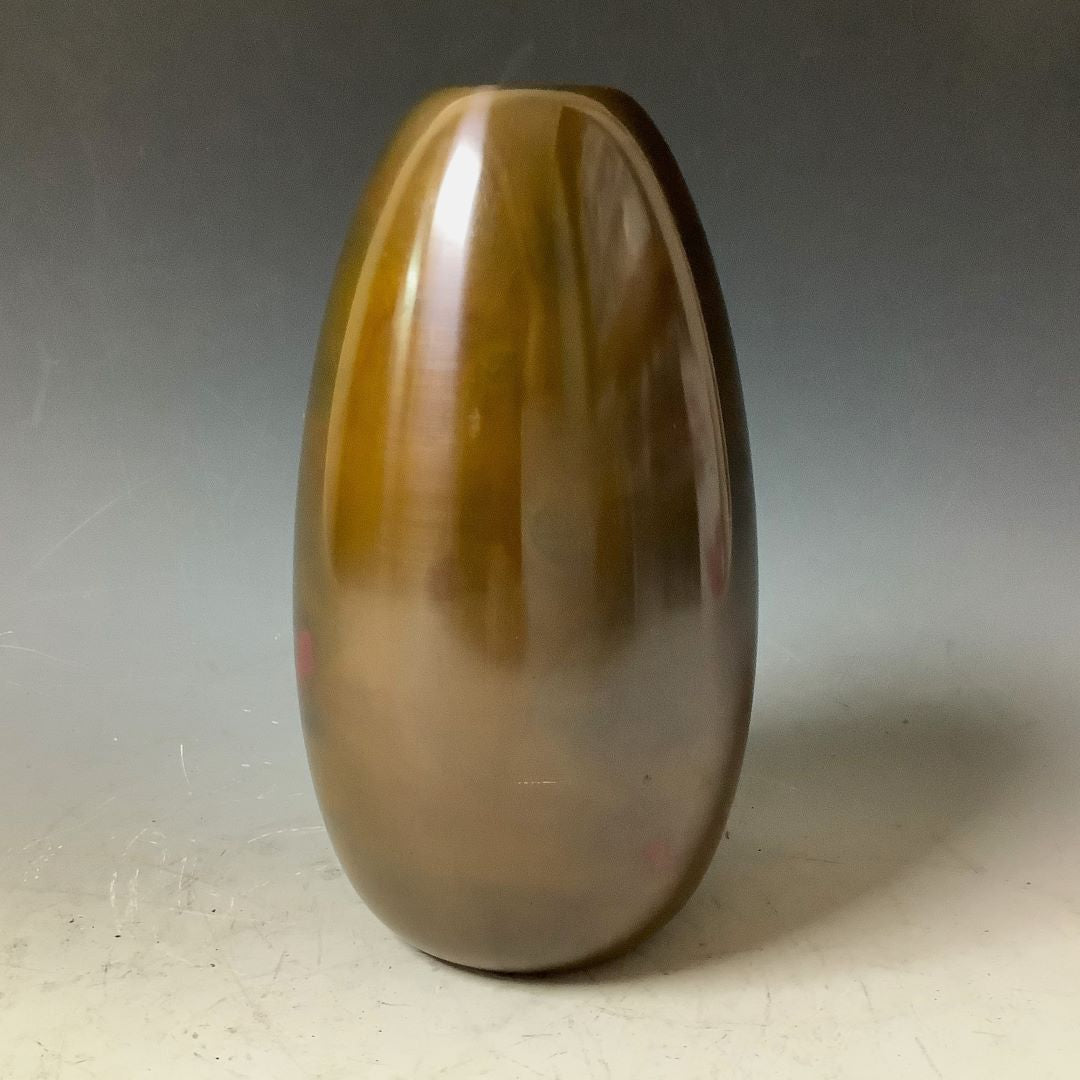 A sleek, polished brown vase with a reflective surface, standing upright against a grey background.