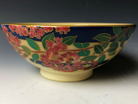 a tea bowl made of ceramic with red lilac flowers and green leaves