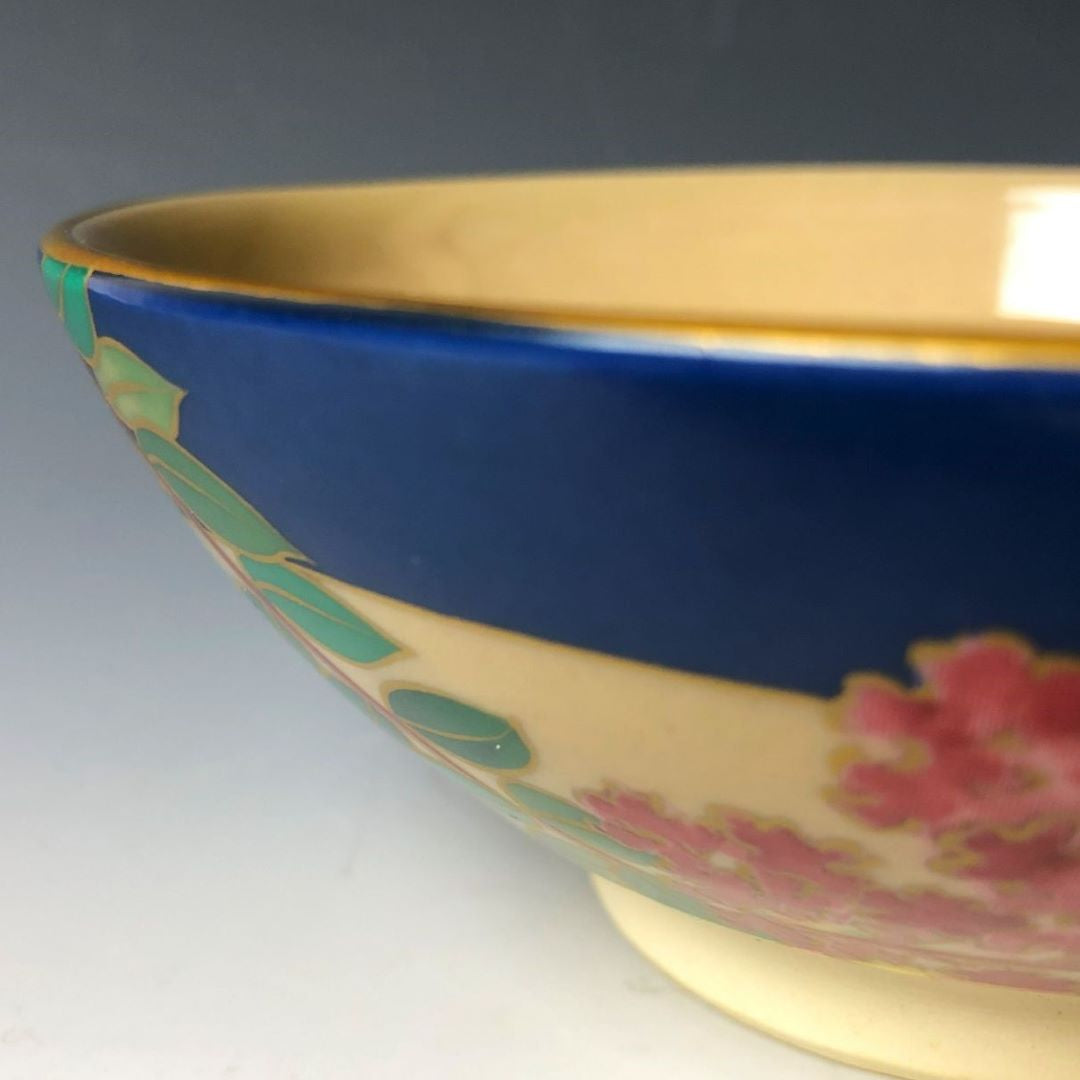 side of a tea bowl with red flowers and green leaves