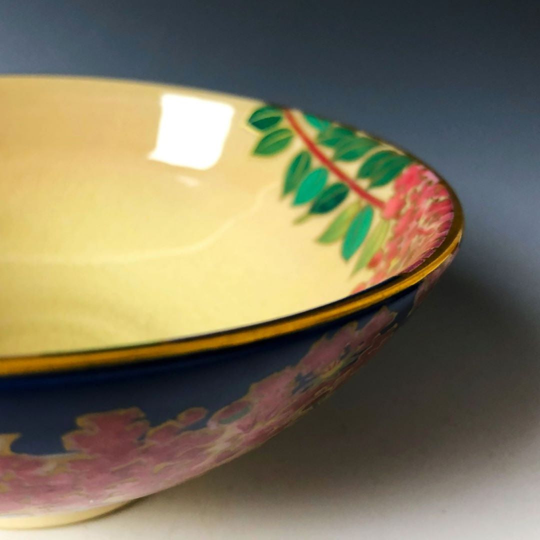 side of a tea bowl with red flowers and green leaves