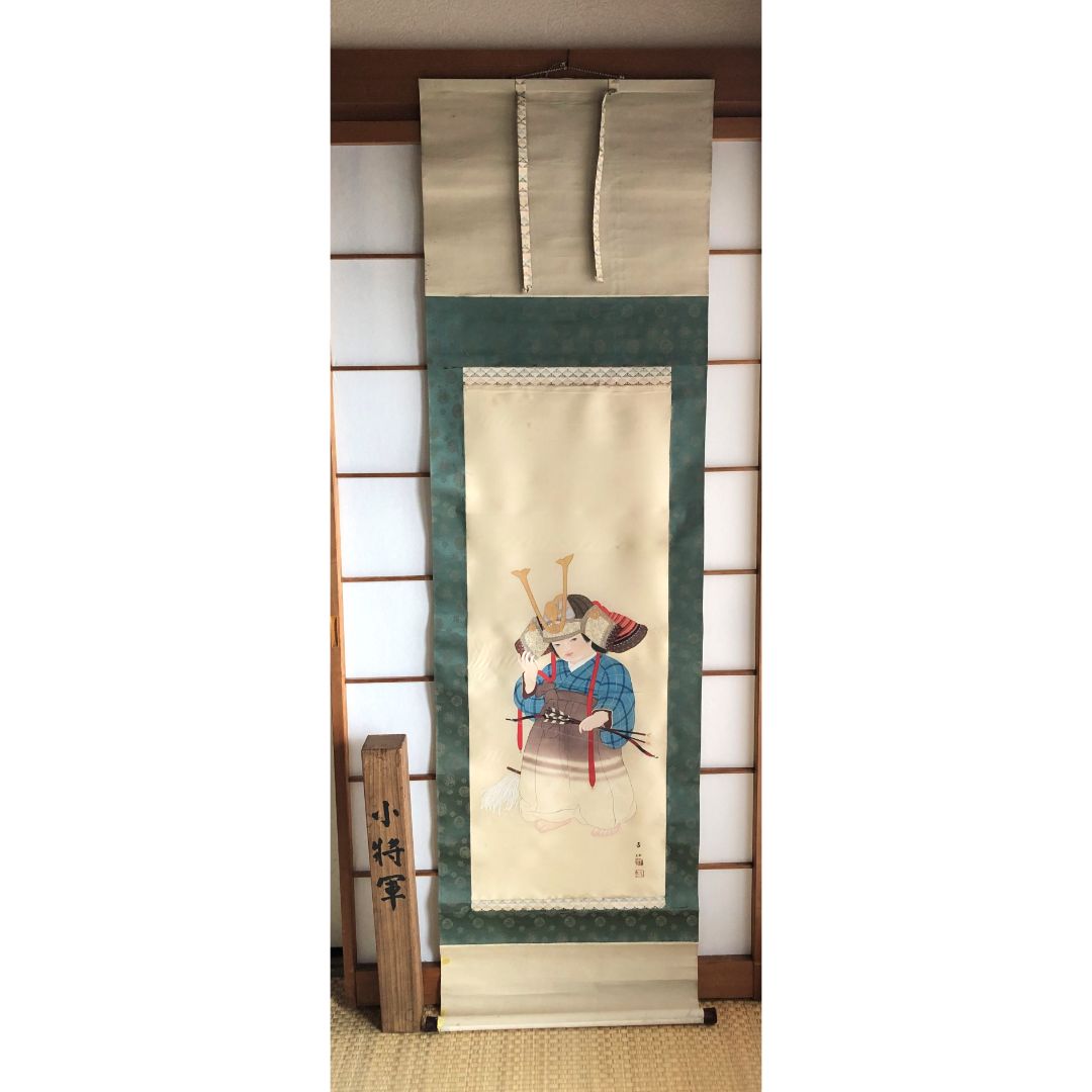 A Japanese art roll painting of child with a helmet in a tatami room